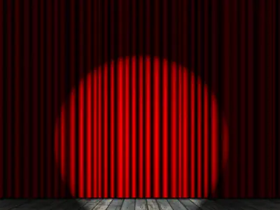 Stock Image - City of Peterborough - Round Spotlight Shining on a Stage with Red Curtain in the Background